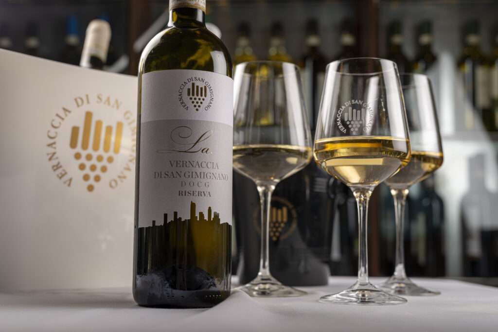 In the foreground, a bottle of white wine and glasses, one of Tuscanys best brand to taste wine.